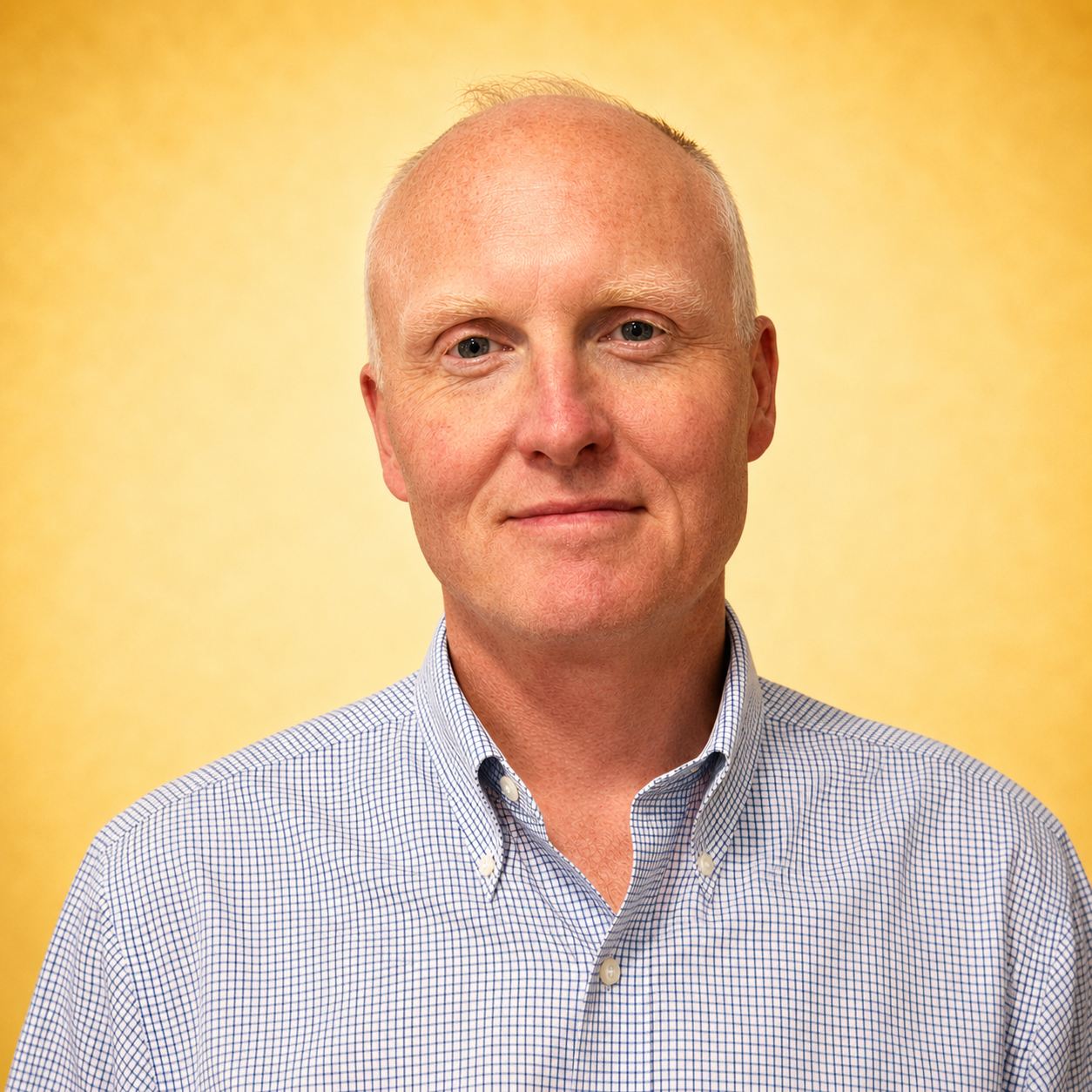 A person in a checked shirt stands against a golden background.
