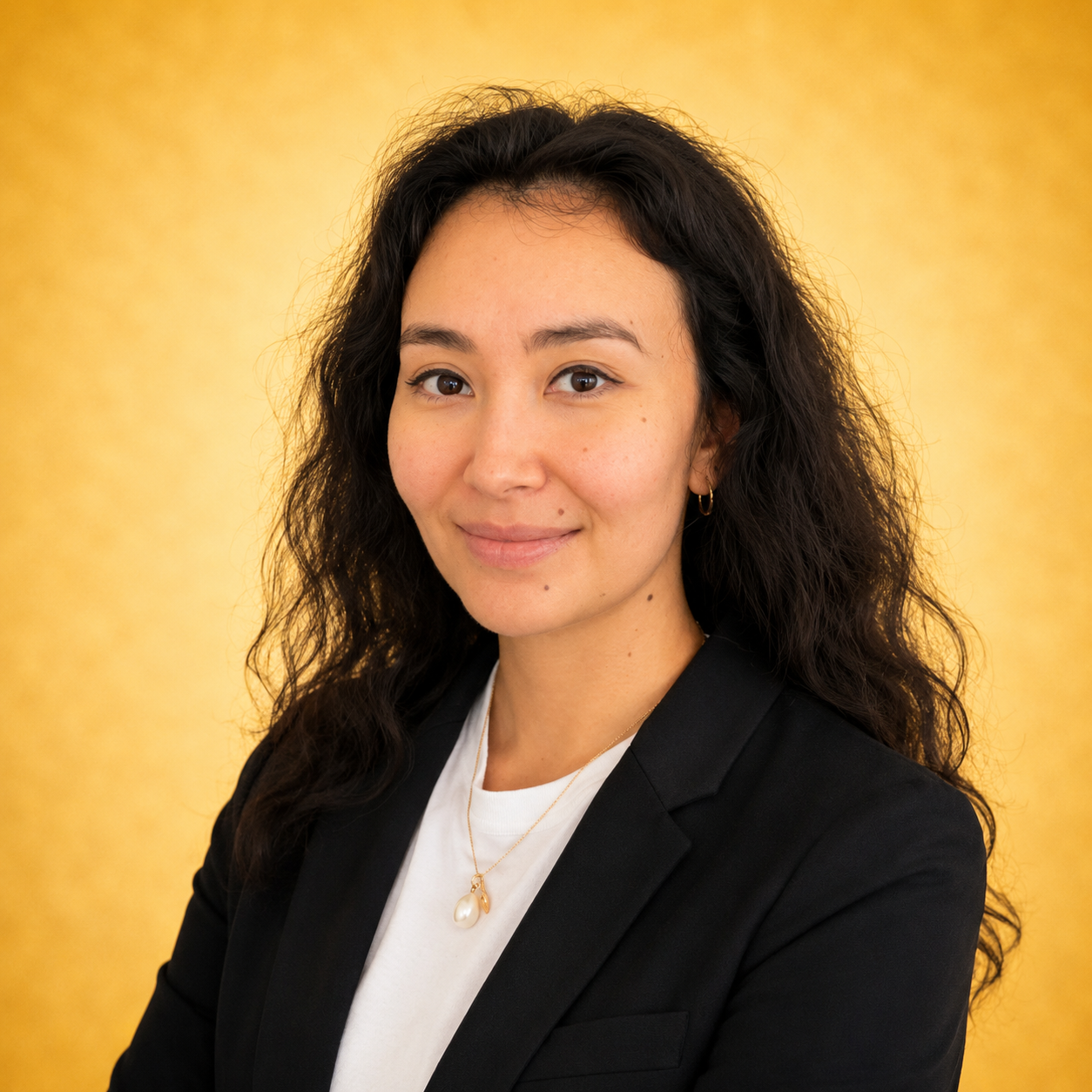 A woman in a black blazer smiling, with a yellow background.