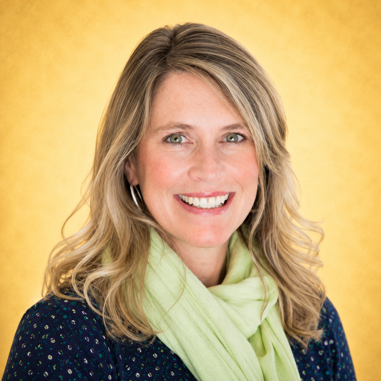 A woman smiling against a yellow background.