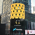 Yellow Gucci billboard on curved building above Nasdaq display in urban financial district